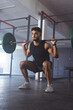 © Wavebreak Media - Strong and fit biracial man at gym lifting weights in squat position