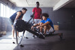 © Wavebreak Media - At gym, diverse men working out together, one using rowing machine