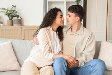 Wall Mural - Young couple in love hugging on sofa at home