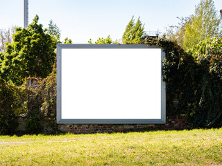 Empty billboard for an advertisement mockup. Template with a free space to test the ad content. There are no people in the image and the subject is next to an overgrown wall.