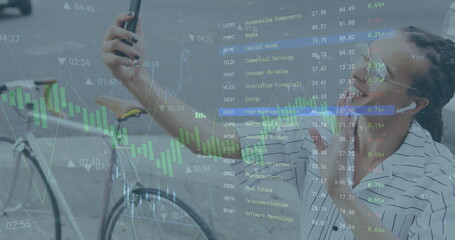 image of graphs and trading board over biracial ma vlogging on cellphone