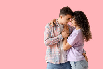 Wall Mural - Young couple in love hugging on pink background