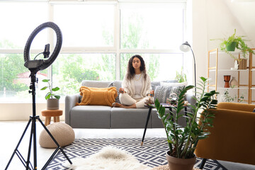 Wall Mural - Young African-American witch meditating while recording video at home