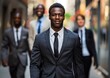 © Qstock - Confident African Businessman Leading Team on City Street