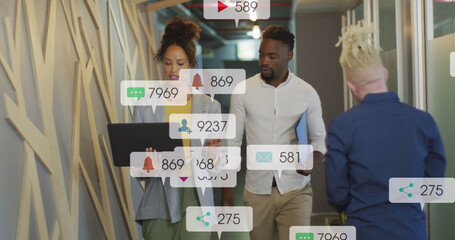 Canvas Print - Image of social media icons on african american man and woman discussing over a laptop at office