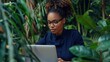 © WS Studio 1985 - business woman with glasses, wearing a sophisticated navy blue dress, seated at her desk and typing on her laptop with a thoughtful expression