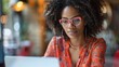 © WS Studio 1985 - business woman with glasses, wearing a vibrant coral blouse, seated at her desk and typing on her laptop with a determined expression