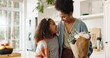 © peopleimages.com - Kitchen, mother and girl with smile, flowers and present for mothers day, love and family in house. Home, mom and daughter with embrace, happiness and cute in apartment, woman or child with gift