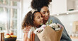 © peopleimages.com - Kitchen, mother and girl with hug, flowers and present for birthday, love and family in house. Home, mom and daughter with embrace, happiness and cute in apartment, woman and child with smile