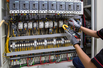 Wall Mural - Electricity and electrical safety maintenance service system, Technician hand checking electric current voltage at circuit breaker terminal and cable wiring in main power distribution board.