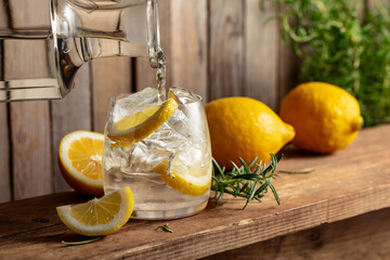 Wall Mural - Water is poured from a decanter into a glass with ice and lemon slices.