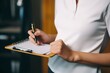 © alisaaa - Woman hand writing on clipboard with a pen. Cropped shot of an unrecognizable businesswoman making notes on a clipboard inside of the office