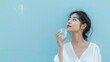 © mongkonchai - Asian woman holding a glass of water on a blue background