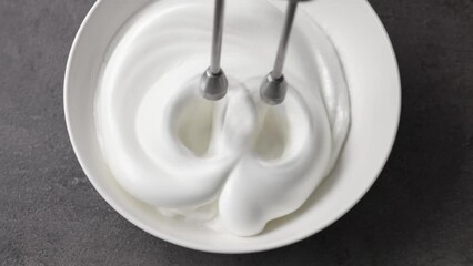 Sticker - Chef whips raw egg whites with powdered sugar in a white bowl with a mixer, top view. Close-up of food