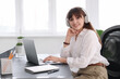 © New Africa - Woman in headphones watching webinar at table in office