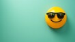 © Nasreen - cool emoji on a mint green background with ample space for text The emoji is yellow with black sunglasses