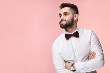 Wall Mural - Portrait of smiling man in shirt and bow tie on pink background. Space for text