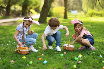 Wall Mural - Easter celebration. Cute little children hunting eggs outdoors