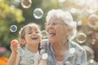 © ChaoticMind - Bright and happy scene of a senior woman with white hair blowing bubbles with a young child in sunlight