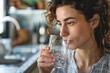 © ChaoticMind - A casual, candid photo of a young woman sipping water from a glass, showcasing hydration and health