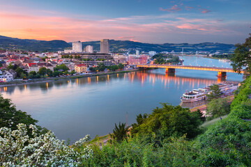 Wall Mural - Linz, Austria. Aerial cityscape image of riverside Linz, Austria during spring sunset with reflection of the city lights in Danube river.
