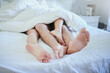 © peopleimages.com - Couple, feet and bed in a home with sleeping, morning and love together in a bedroom. Romance, passion and care of people legs under a duvet and blanket with marriage, cuddle and nap in a house