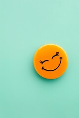 Wall Mural - winking emoji on a mint green background with space for copy The emoji is bright orange, adding a playful touch
