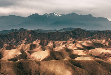 Wall Mural - The aerial view of mountain peaks and the snow-capped mountain in the distance in Ziniquan region in Xinjiang in overcast weather