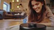 © JR-50 - Smiling Woman Watching Robot Vacuum Cleaner in Modern Living Room