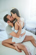 © peopleimages.com - Passion, morning and couple in bed with kiss, romance and happy bonding in apartment. Relationship, man and woman in bedroom with intimate embrace, affection and love with care on weekend in home