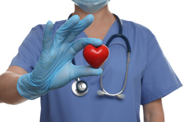 Doctor wearing light blue medical glove holding decorative heart on white background, closeup