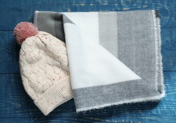 Poster - Soft scarf and knitted hat on blue wooden table, top view