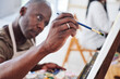 © peopleimages.com - Artist, mature or black man painting on canvas or easel for therapy, drawing or studio project. Creative, painter or African person with brush, class and talent for design or watercolor in workshop
