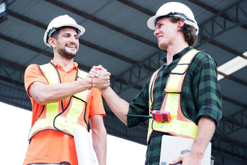 Engineer wearing safety helmet stands smiling at construction site.