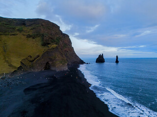 Black sand beach with the two rocks and cliffs from the air, Reynisfjara Beach, Iceland.