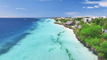 Wall Mural - Aerial view of sandy beach, blue sea, bungalows, green palms, umbrellas, floating boat at sunset. Summer travel in Nungwi, Zanzibar island. Tropical landscape. Top drone view of luxury resort. Ocean