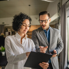 Colleagues stand in cafe woman hold document and man hold mobile phone