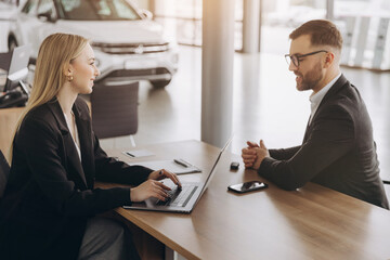 Smiling happy female manager car salesman in car dealership signing contract at table with male buyer in suit