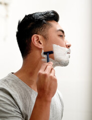 Man, shaving in home and skincare with cream in bathroom, maintenance and beard aesthetic for grooming. Asian, person and hair removal for facial cleaning foam, growth control and hygiene treatment