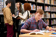 © peopleimages.com - Student, writing and notebook in library for study, education and university quiz with pen on table. Man, books and knowledge on school campus for college exam, research and learning with scholarship