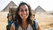 © esp2k - A smiling woman with a backpack is posing in front of the pyramids of Egypt