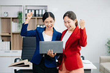 Two business workers talking on the smartphone and using laptop at office