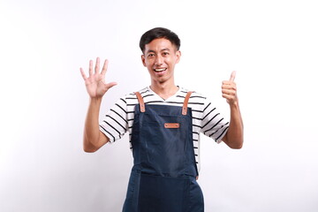 Asian young man wearing apron over white background showing six fingers with exited and happy face expression