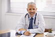 © peopleimages.com - Mature, man and portrait of doctor in office with pride for hospital, medicine and document. Prescription, stethoscope and paperwork for medical expert, insurance and admin with smile for healthcare