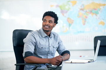 Fototapete - Business, thinking and black man with laptop, ideas and planning at international agency. Research, consultant or travel agent at desk with info in notebook for schedule, agenda or online booking