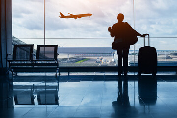 travel by plane, woman passenger waiting in airport, silhouette of passenger in airport watching aircraft taking off