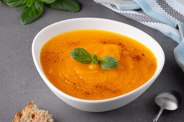 Pumpkin and carrot soup on grey background