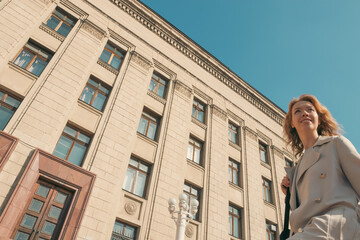 Confident woman in stylish trench coat walking in city street