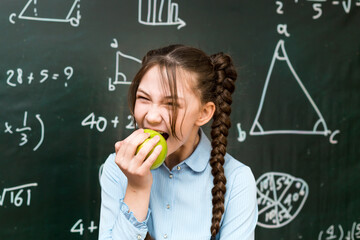 Girl bites an apple, vegetarian food at school.