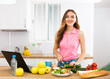 © caftor - Positive woman cooking dinner and using laptop
